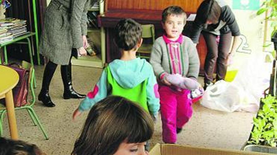 Los escolares de El Valle, depositando juguetes. Abajo, una niña, reciclando.