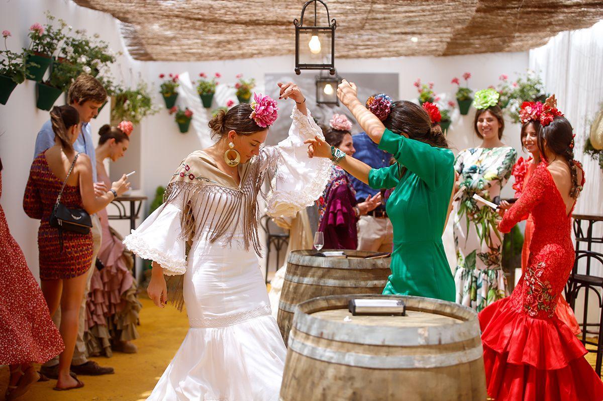 Mujeres ataviadas con trajes de gitana bailan sevillanas en una caseta de la Feria de Córdoba, este sábado.