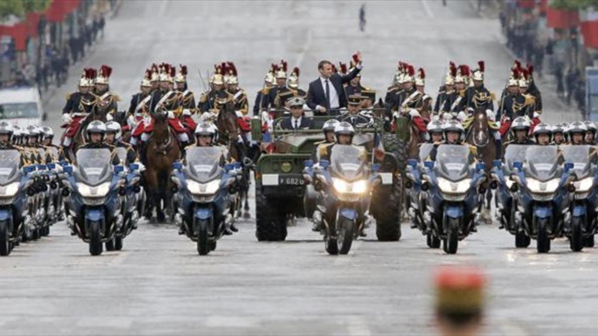 Macron saluda desde un vehículo militar a su paso por los Campos Elíseos.