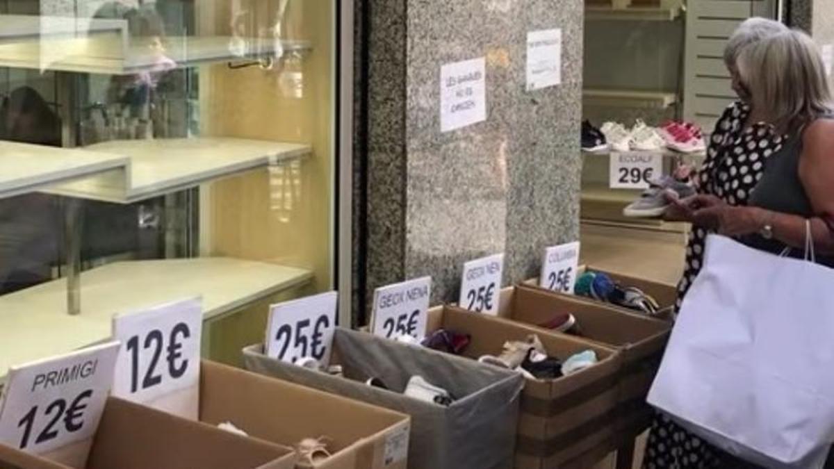Dues clientes es miren unes sabates en una parada al carrer
