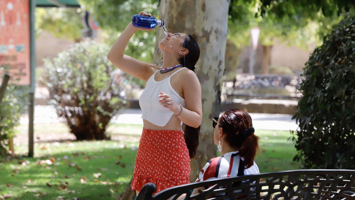 Una joven se refresca con agua de una botella en unos jardines de Córdoba.