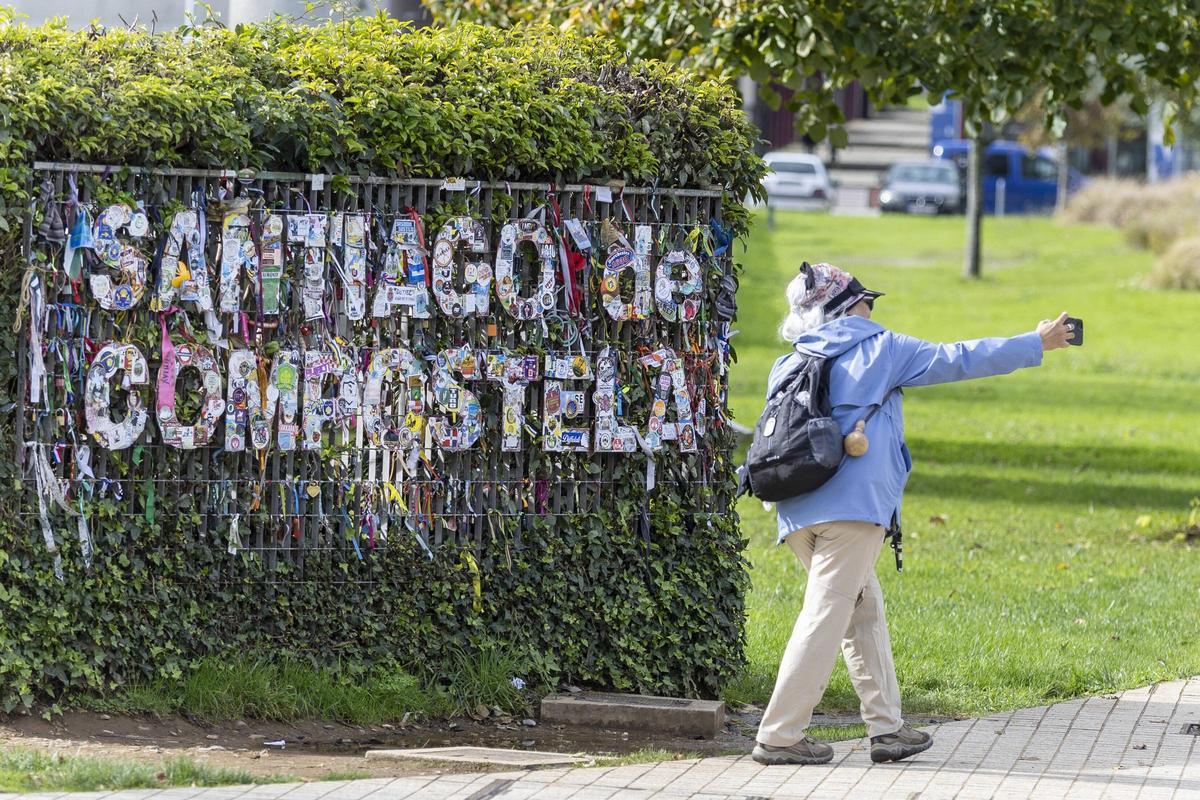 Una peregrina se saca una foto en la entrada de Santiago por San Lázaro
