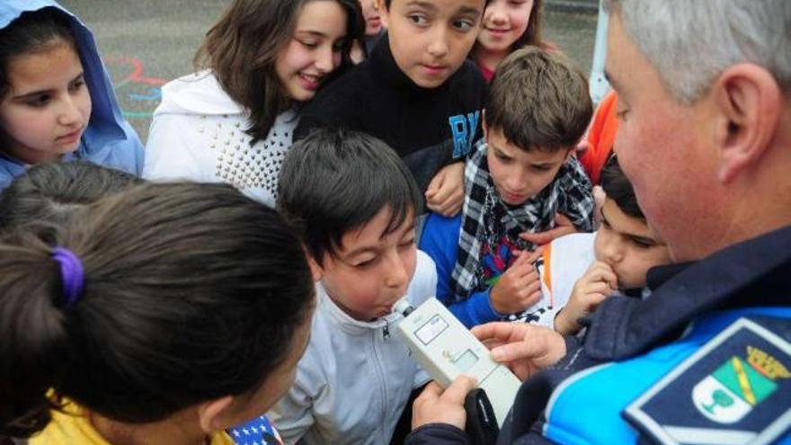 Varios niños contemplan a un compañero que simula realizar la prueba de alcoholemia.  // Bernabé/J. Lalín