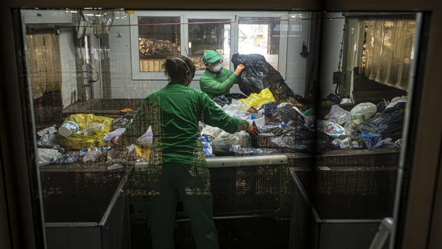 Dos treballadors revisen residusen la planta de triatge d’envasos de Gavà-Viladecans.