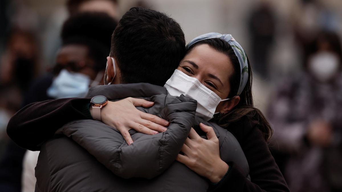 Dos personas con mascarillas se abrazan en la calle a falta de dos días de que entre en vigor su obligatoriedad en exteriores.