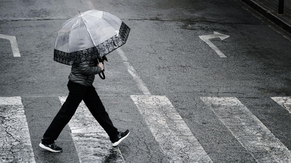 Persona protegiéndose de la lluvia con un paraguas.