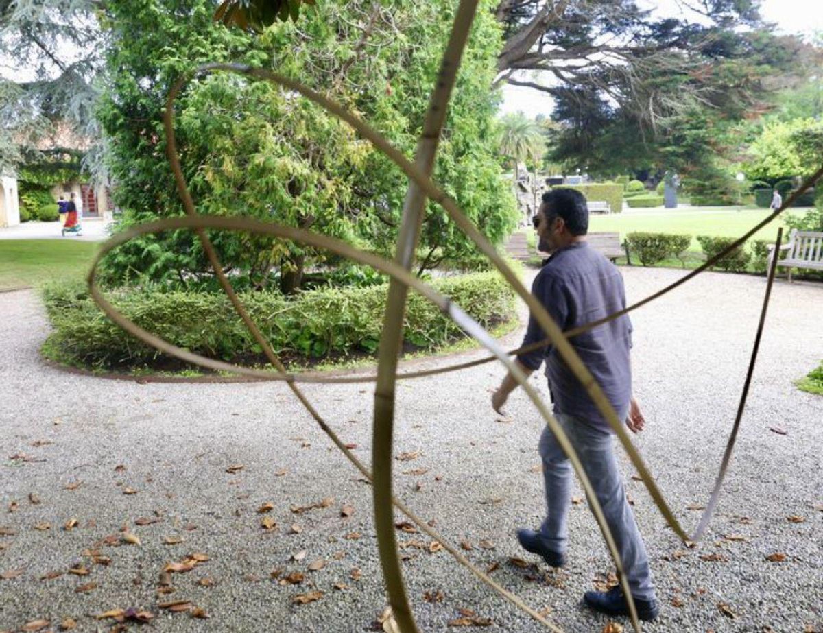 Un hombre pasa ante una pieza instalada en el jardín. | MARCOS LEÓN