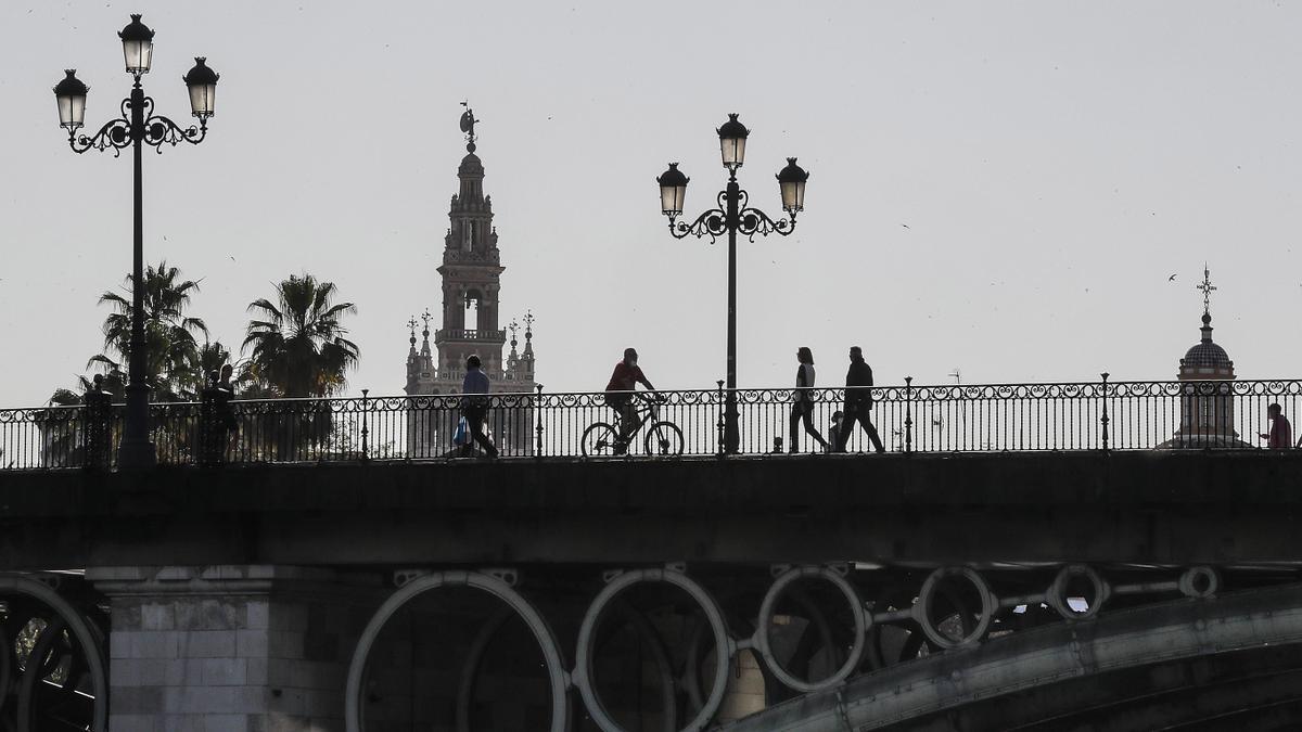 Imagen de un grupo de personas, por el Puente de Triana.