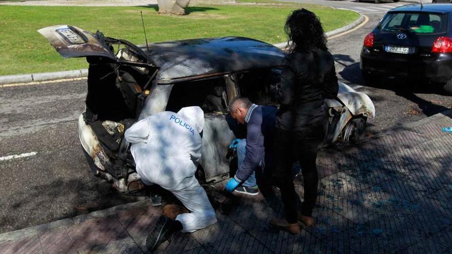 Agentes de la Policía científica, ayer, analizando los restos del coche quemado en Villafría.