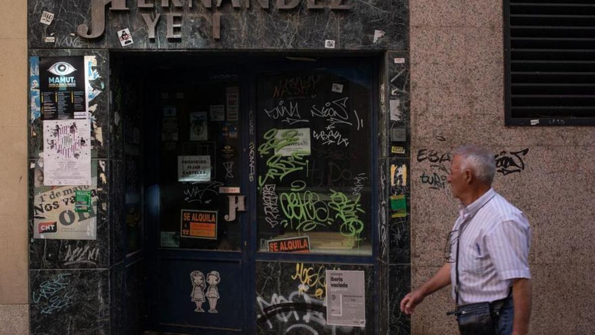 Un hombre mira la fachada de un antiguo negocio familiar en Zamora.