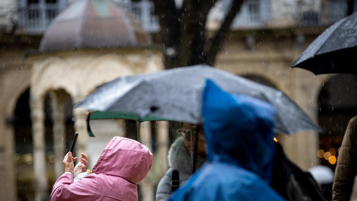 Un grupo de turistas trata de protegerse de la lluvia.