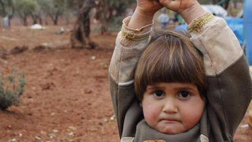 Un niño sirio levanta los brazos en señal de rendición.