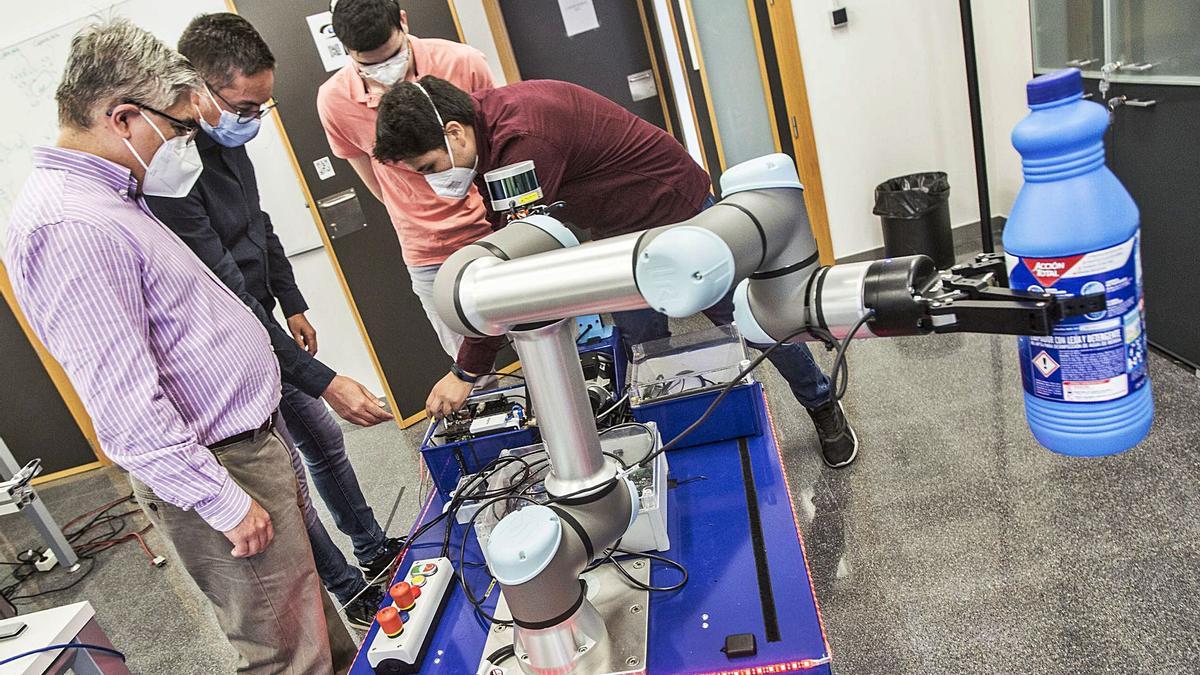 El grupo Automática, Robótica y Visión Artificial de la UA, con el robot para recogida de basuras que han construido a partir de una carretilla. | PILAR CORTÉS