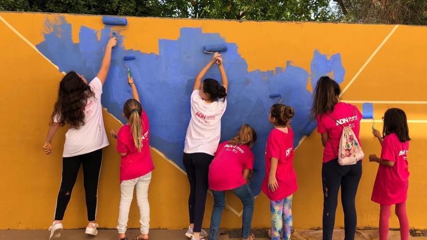 Niños pintan un mural en la pared.