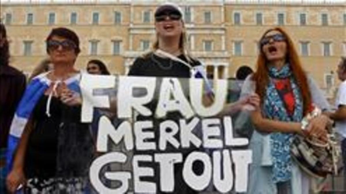 Tres mujeres sostienen una pancarta contra Merkel, este martes en el centro de Atenas.