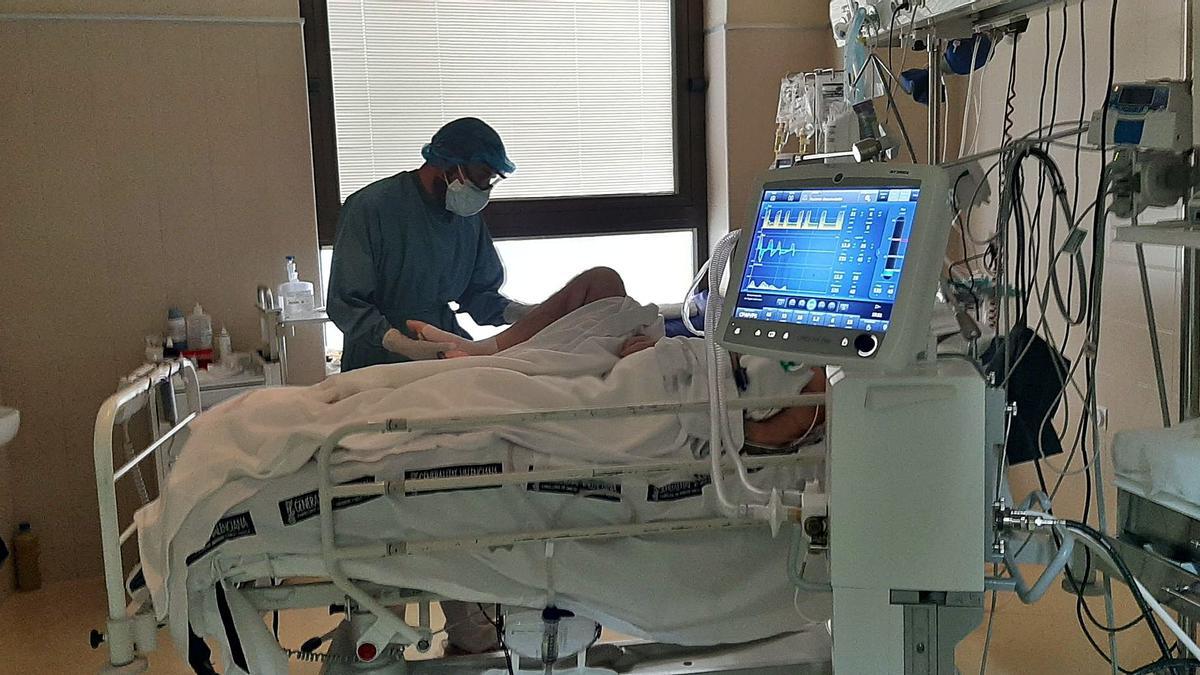 Un sanitario atiende en la UCI del hospital de Elche a un paciente infectado por covid, en una imagen reciente.