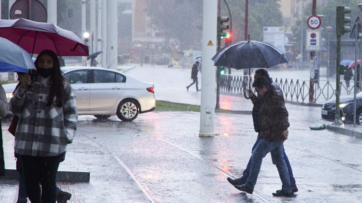 Dos personas se protegen de la lluvia bajo un paraguas en Sevilla.