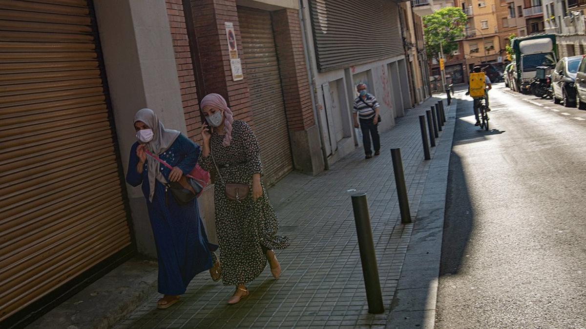 Dos vecinas de L'Hospitalet caminan por una calle casi desierta, el pasado 15 de julio