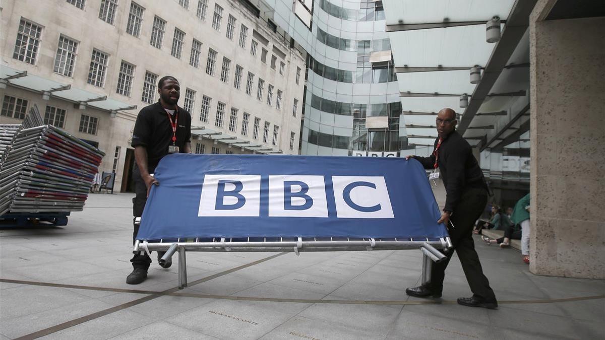 Dos empleados de la BBC sitúan barreras cerca de la entrada principal del cuartel general de la BBC en Portland Place, en Londres, el 16 de julio del 2015.