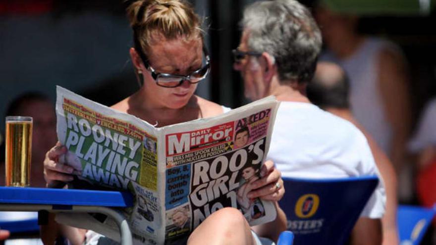 Una turista británica lee la prensa de su país en una terraza de Benidorm.