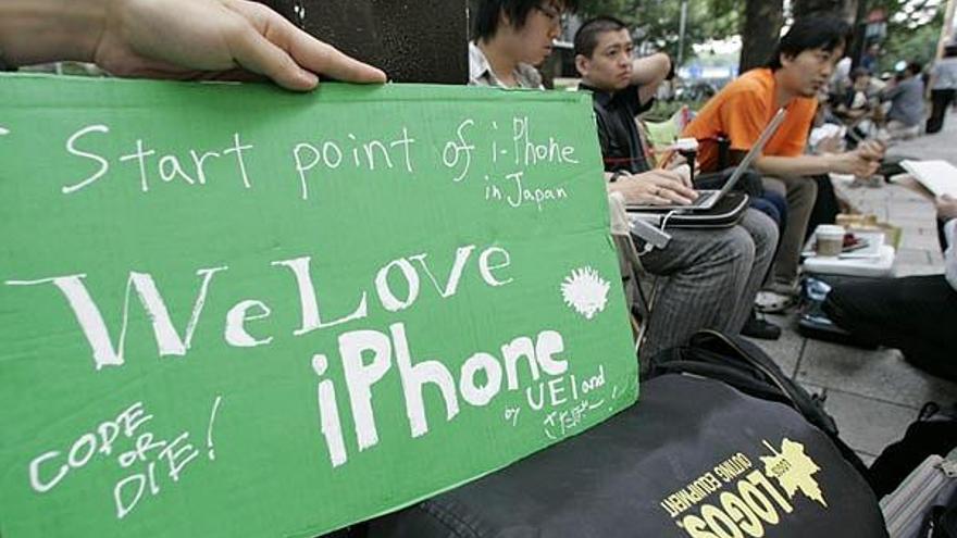 Varios jóvenes hacen cola frente a la tienda de Apple.