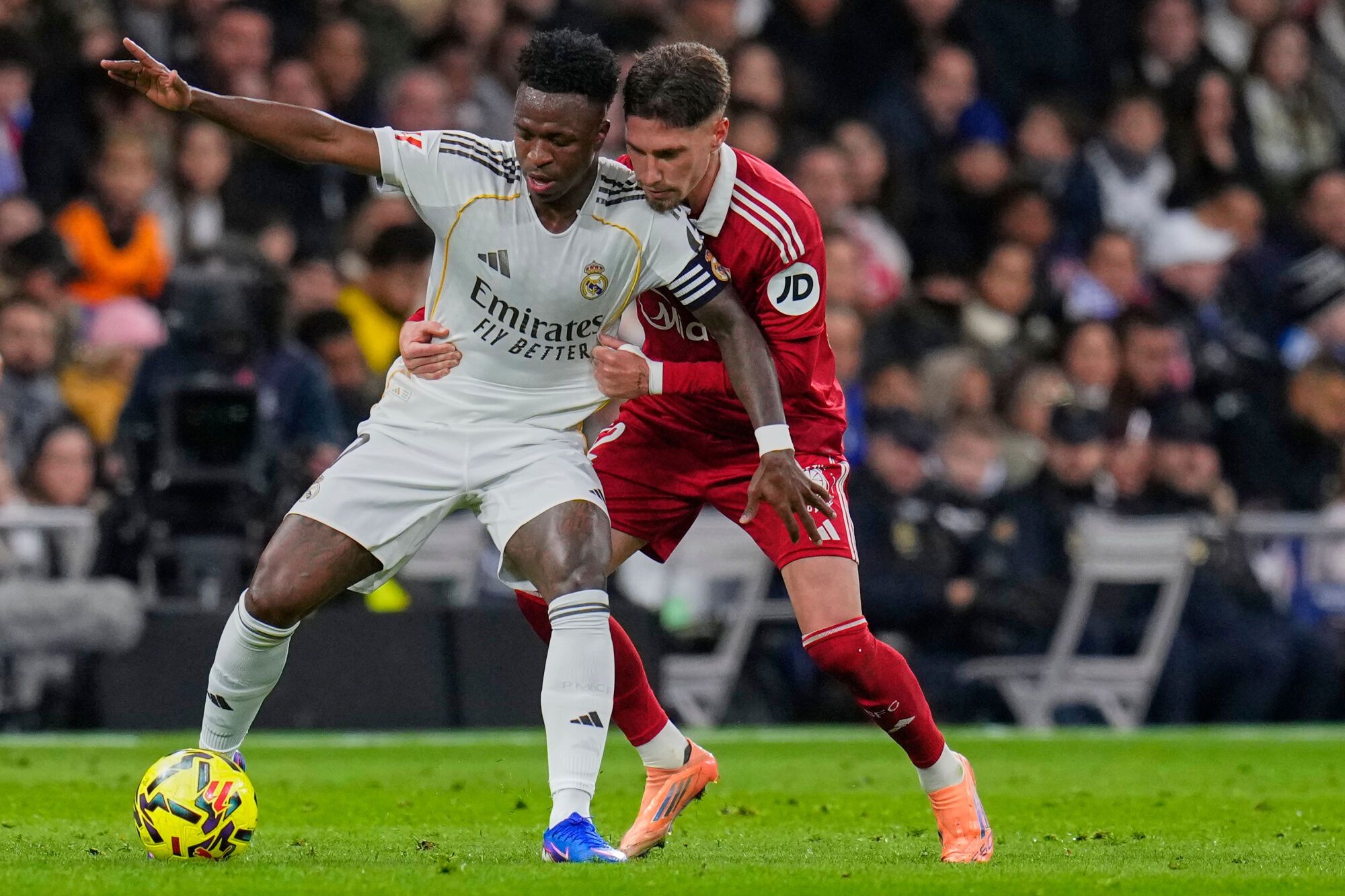Real Madrid's Vinicius Junior, left, holds off the challenge of Sevilla's Jose Angel Carmona during the Spanish La Liga soccer match between Real Madrid and Sevilla in Madrid, Spain, Saturday, Dec. 20, 2025. (AP Photo/Manu Fernandez). EDITORIAL USE ONLY/ONLY ITALY AND SPAIN