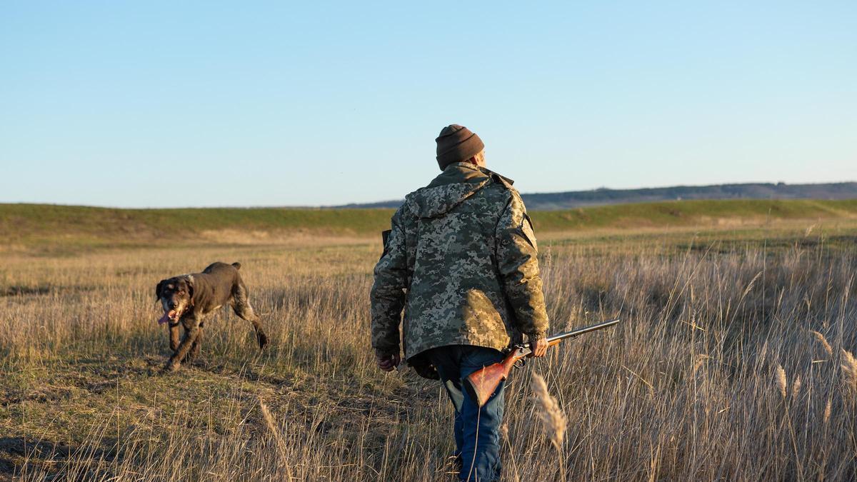 Un cazador busca una presa con su perro.