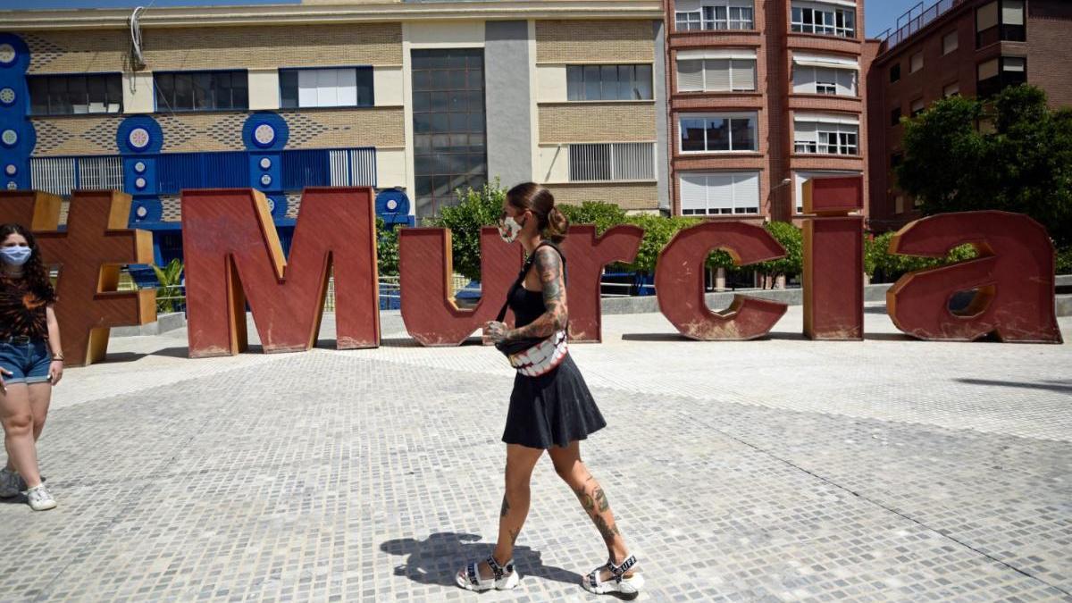 Una mujer camina por la calle con su mascarilla.