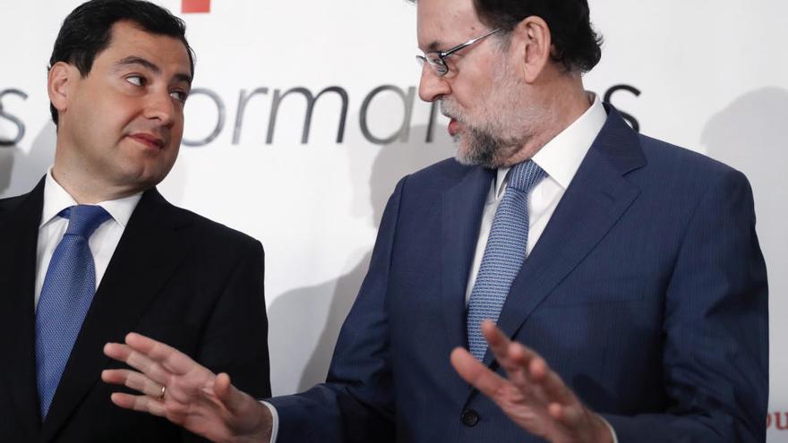 El presidente del Gobierno, Mariano Rajoy (d), conversa con el presidente del PP andaluz, Juanma Moreno (i).