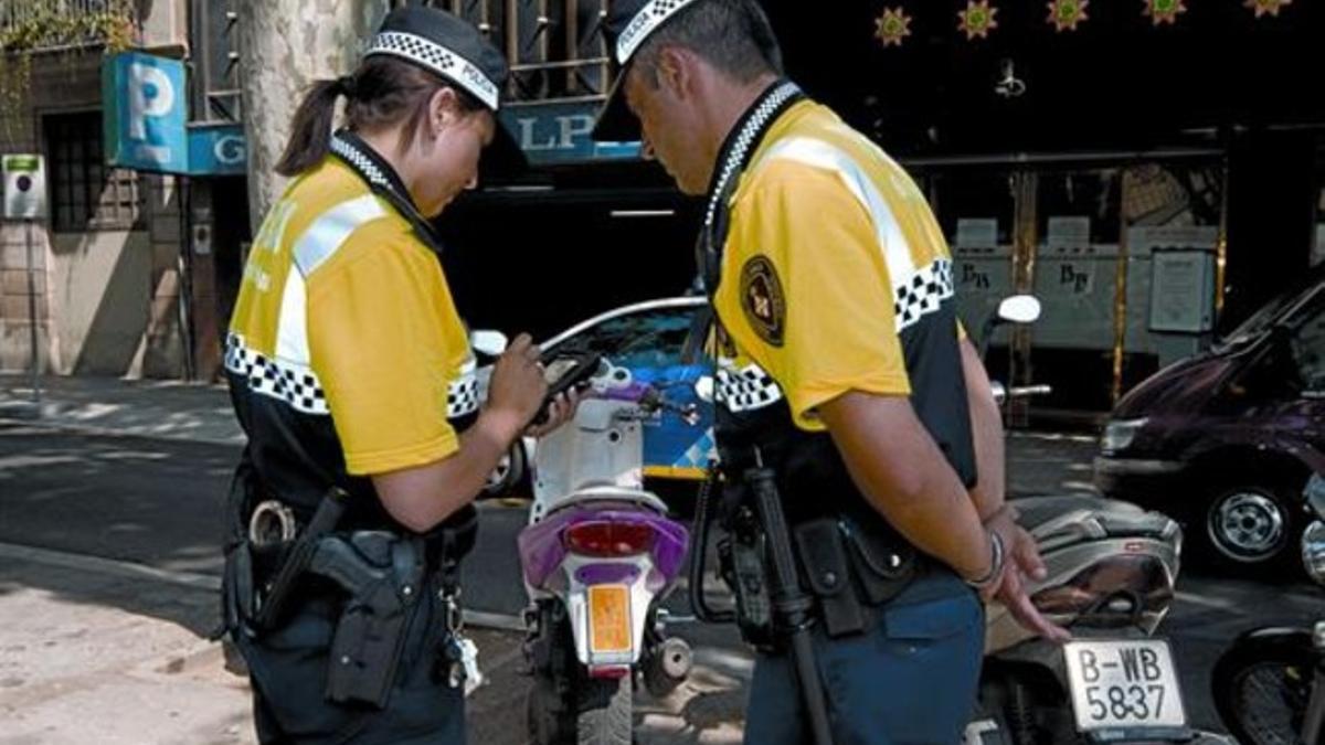 Un agente de la Guardia Urbana imprime el comprobante de la multa que acaba de poner al conductor.