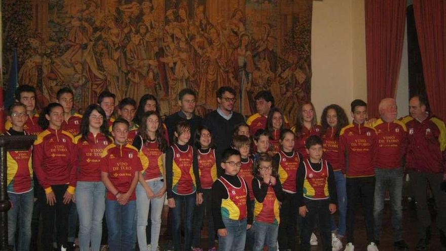 Autoridades locales posan con deportistas del club de atletismo en un homenaje.