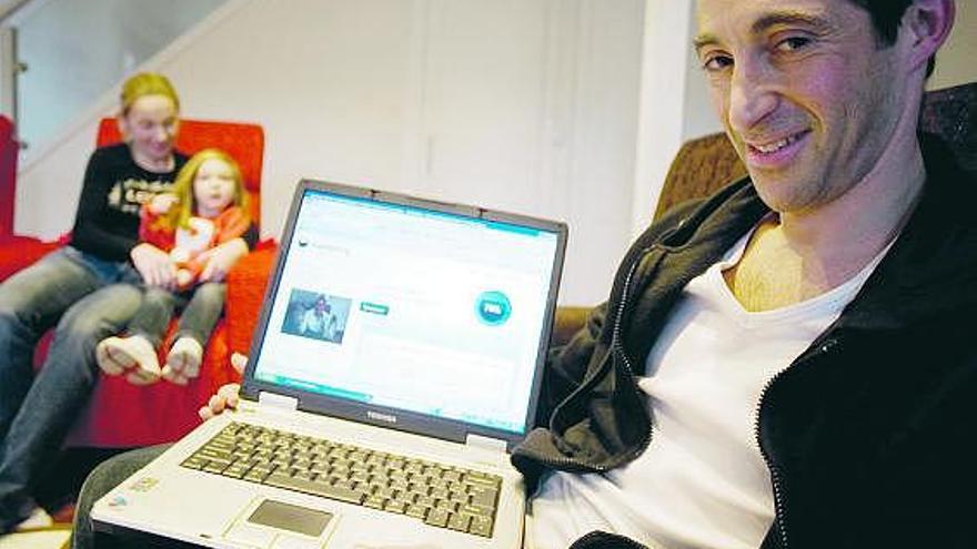 Ilana Hecht, en brazos de su madre, Cristina Suárez, mientras su padre, Anthony Hecht, muestra su página web.