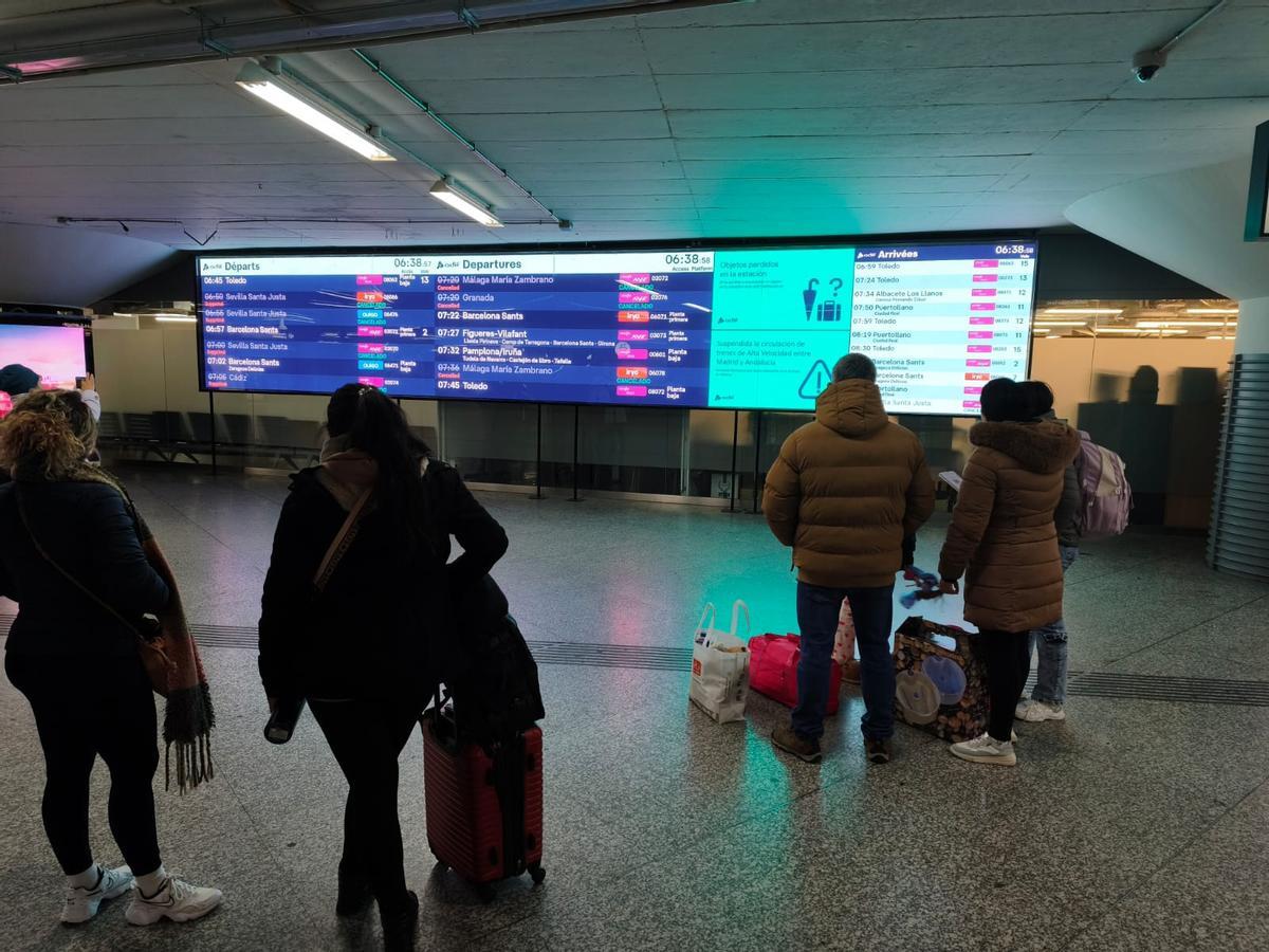 Pasajeros en Atocha miran las pantallas informativas.
