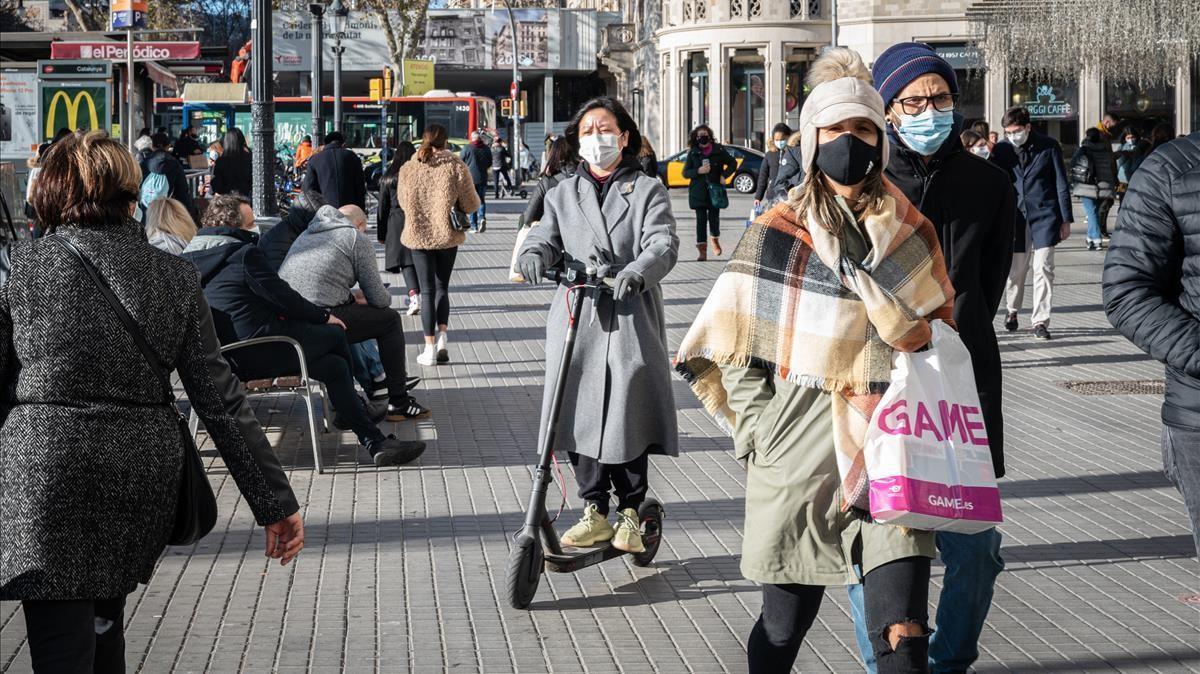 Una mujer circula en patinete por la acera en el centro de  Barcelona, el 4 de enero