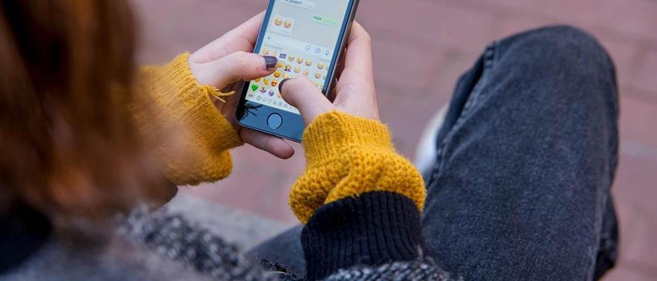 Una chica consulta su teléfono móvil.