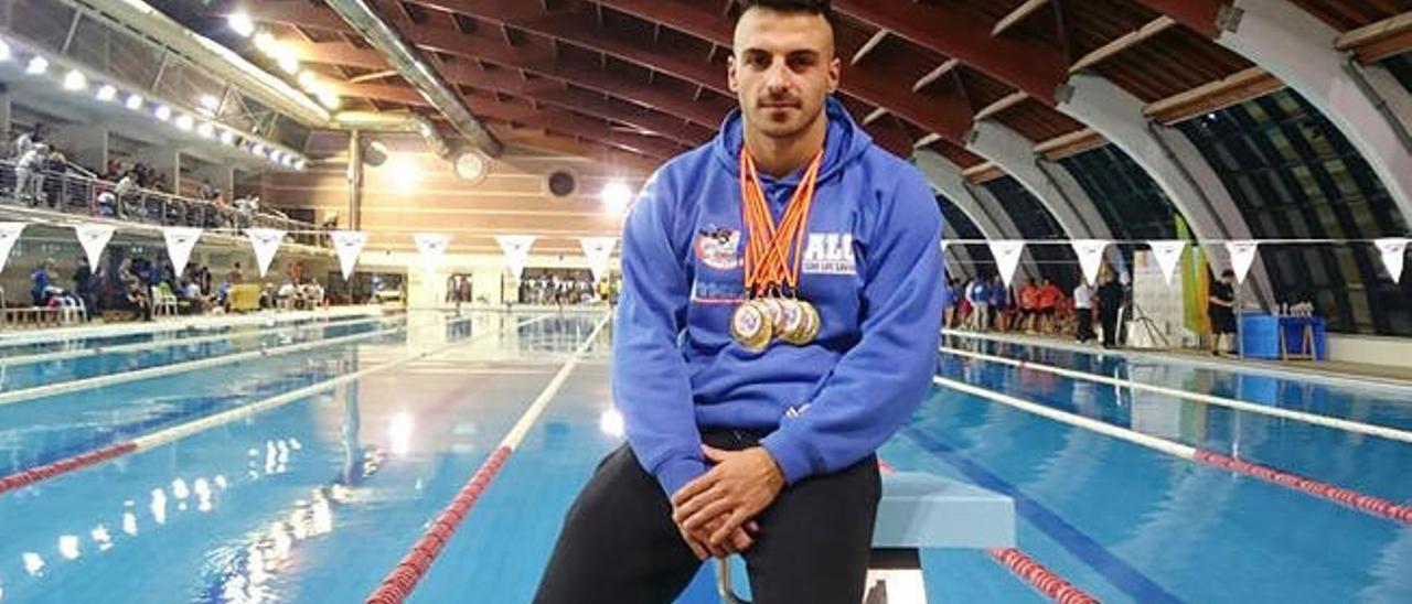 El nadador Eduardo Blasco, con varias medallas conseguidas en una competición, posa en una piscina.