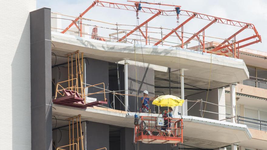 Unos obreros se protegen del sol mientras trabajan en la construcción de un edificio en Alicante