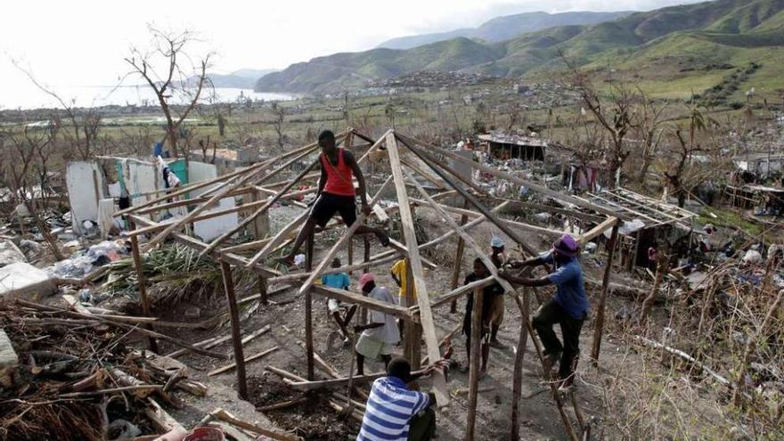 Varios haitianos tratan de levantar una casa de madera en una zona devastada por el huracán.