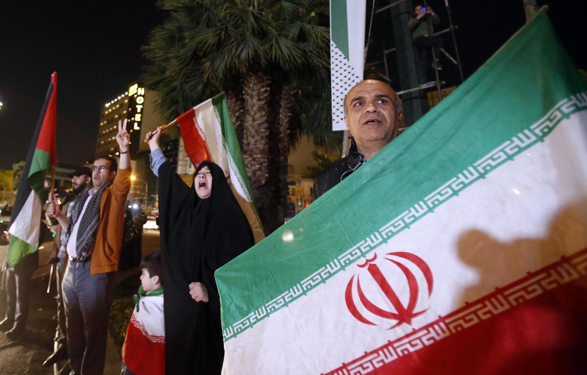 Un grupo de manifestantes sostienen banderas iraníes y palestinas durante una manifestación antiisraelí después de que Irán lanzara ataques con drones contra Israel en la Plaza Palestina de Teherán.
