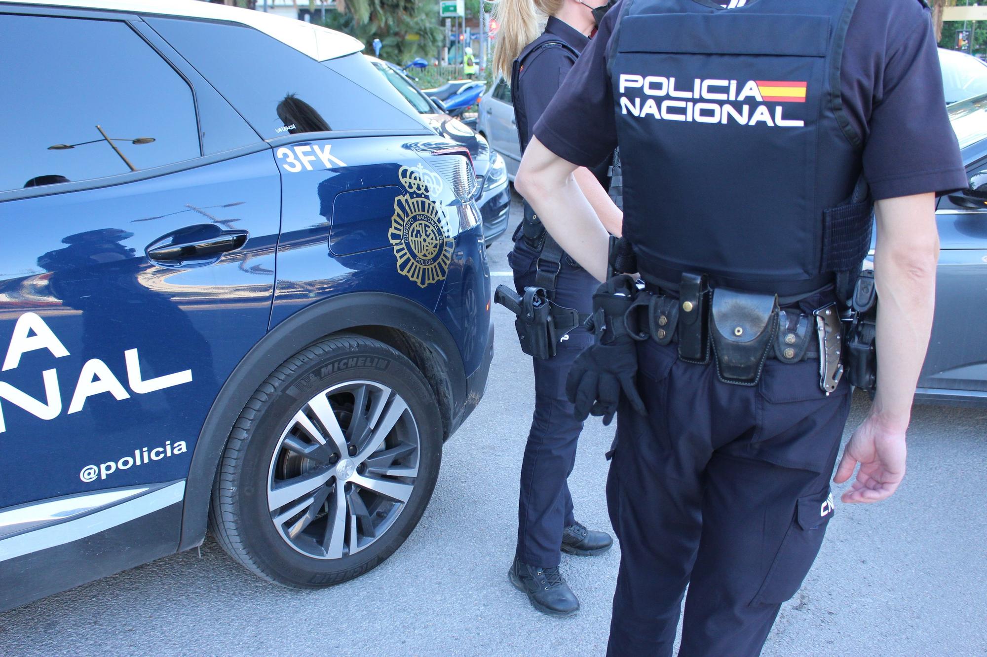 Agentes de la Policía Nacional junto a un vehículo policial.