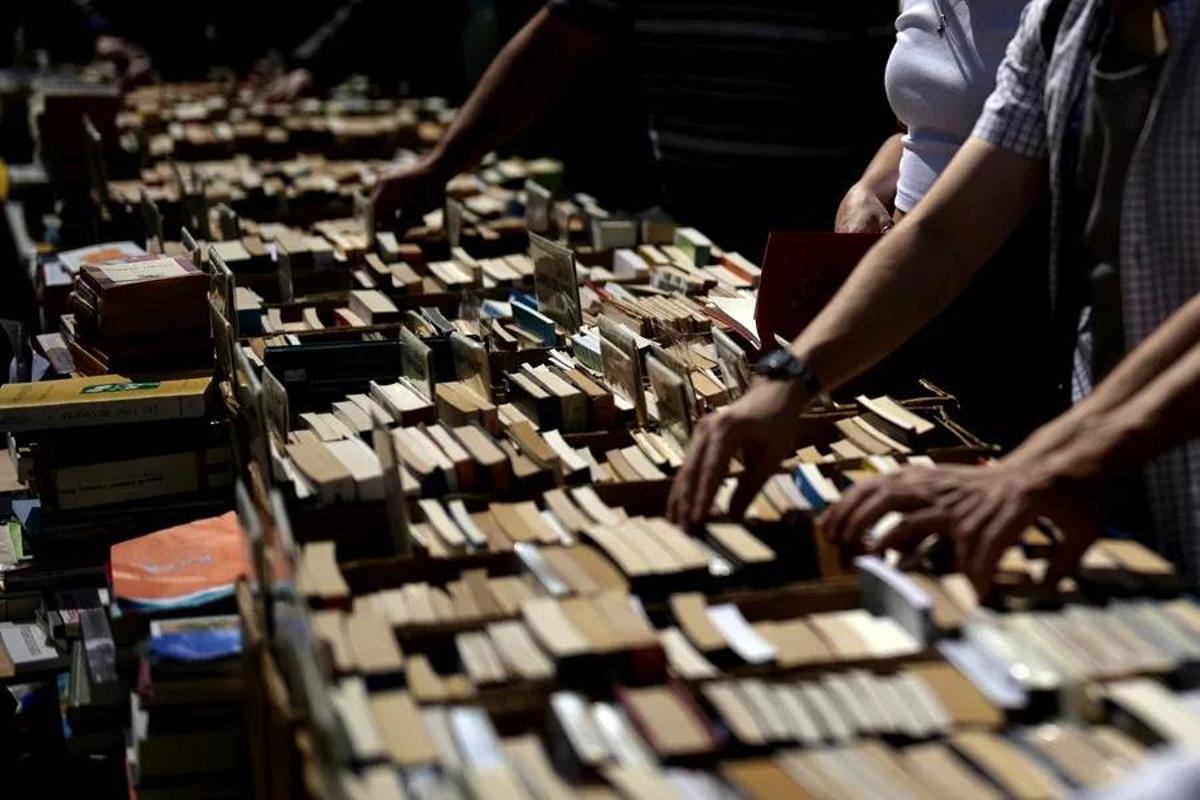 Varias personas buscan libros en una parada en el Paseo de Gracia de Barcelona durante la Diada de Sant Jordi, en la que los catalanes toman las calles a la búsqueda de libros y rosas para regalar a sus seres queridos y allegados