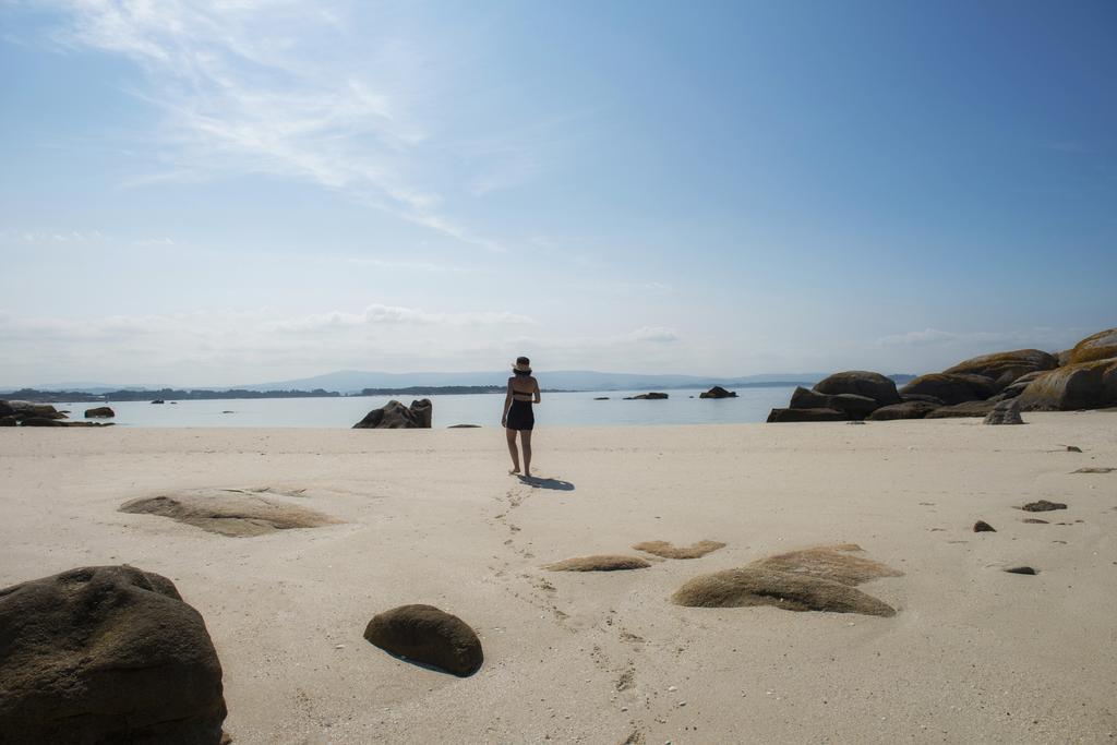 Joven caminando sola en la playa de la isla desierta de Areoso en las Rías Baixas