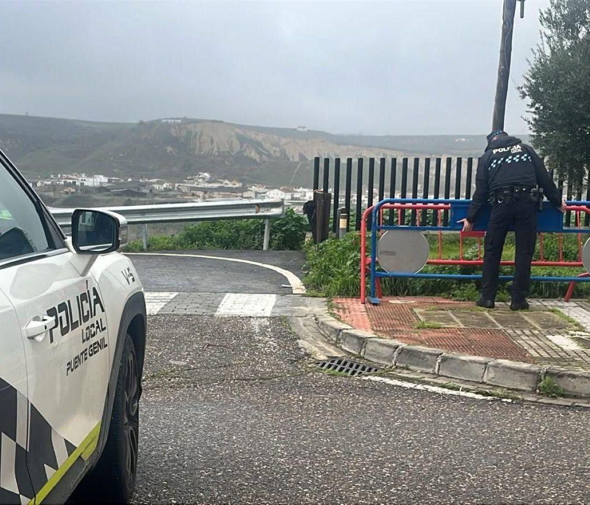 Un policía local de Puente Genil retira una valla que impedía el paso del tráfico.