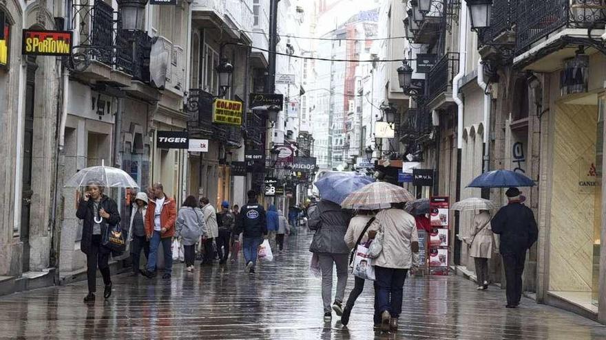 Gente resguardándose de la lluvia en la calle Real.