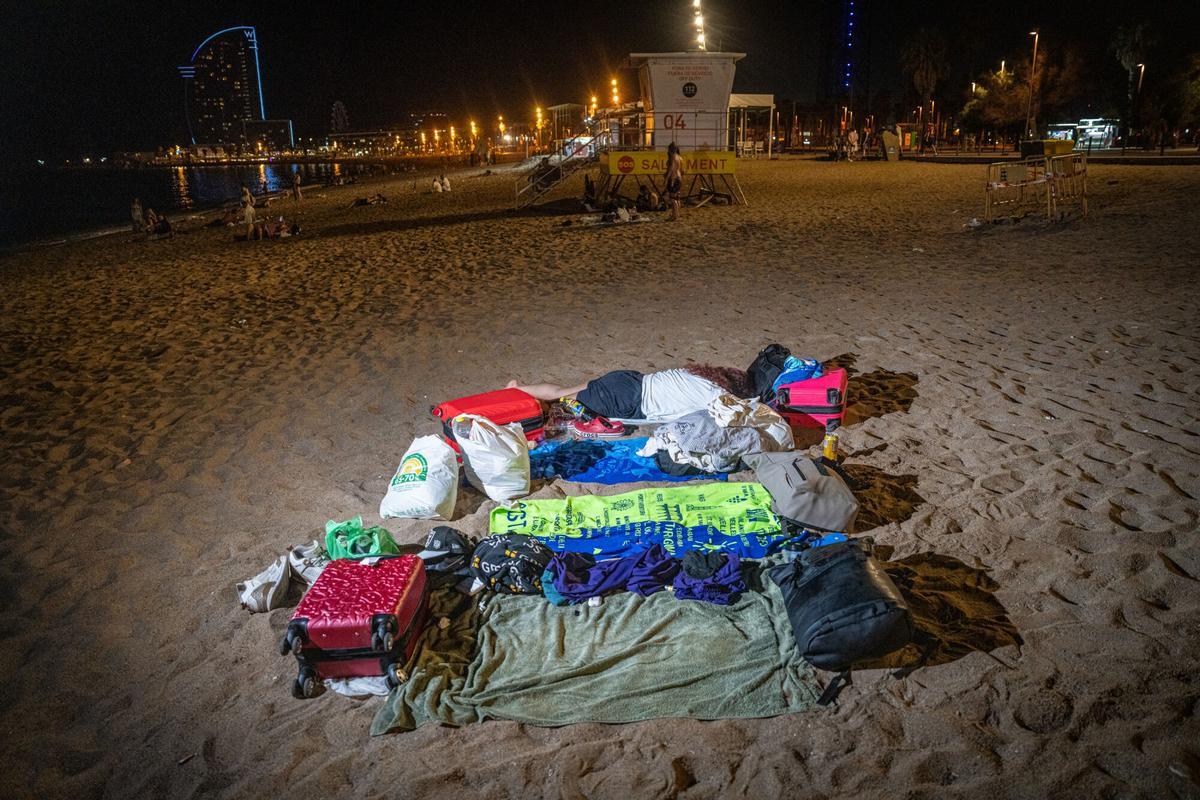 Turistas con maletas pasan la noche en las playas de Barcelona para evitar el coste del alojamiento. La pernoctación en las playas está prohibida y quienes la practican se exponen tanto al riesgo de sufrir robos como a ser desalojados por la Guardia Urbana. A 6 de agosto de 2026. Sociedad. AUTOR: MANU MITRU