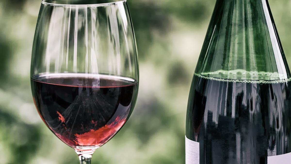 Copa de vino tinto llena junto a una botella