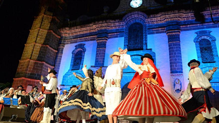 El grupo folclórico Los Labrantes de Arucas, anoche durante su actuación en la fiesta del Pino de Teror; a la derecha el público contempla la actuación musical.