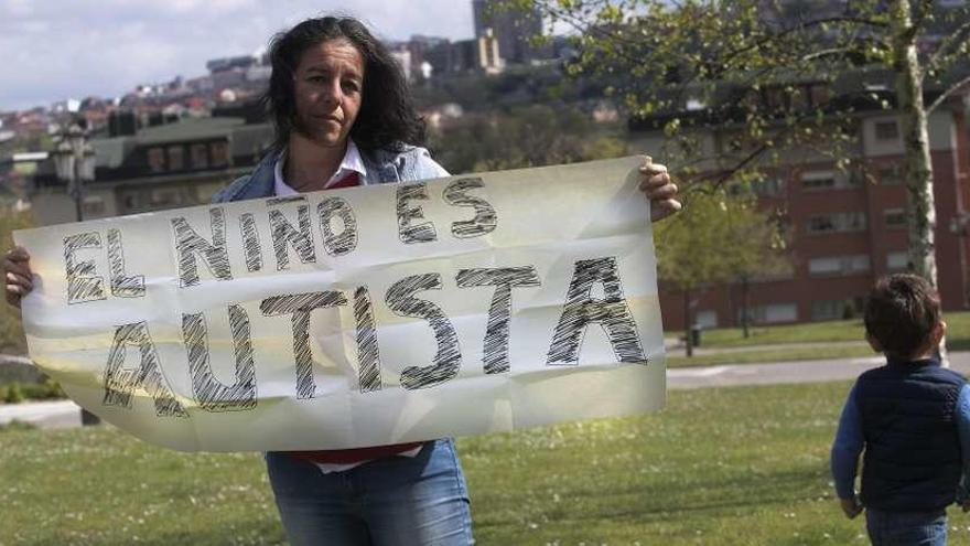 La madre de un niño autista de Oviedo muestra el cartel con el que se protege de las críticas de sus vecinos.