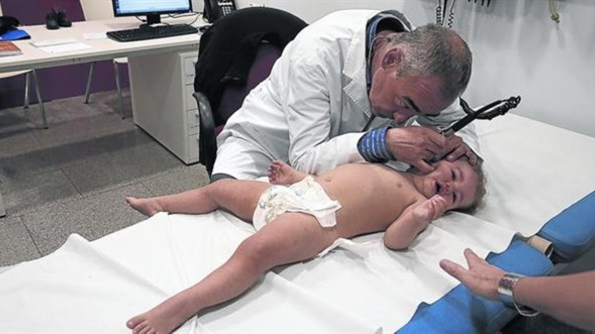 Un médico ausculta a una niña, ayer en el Hospital de Nens de Barcelona.