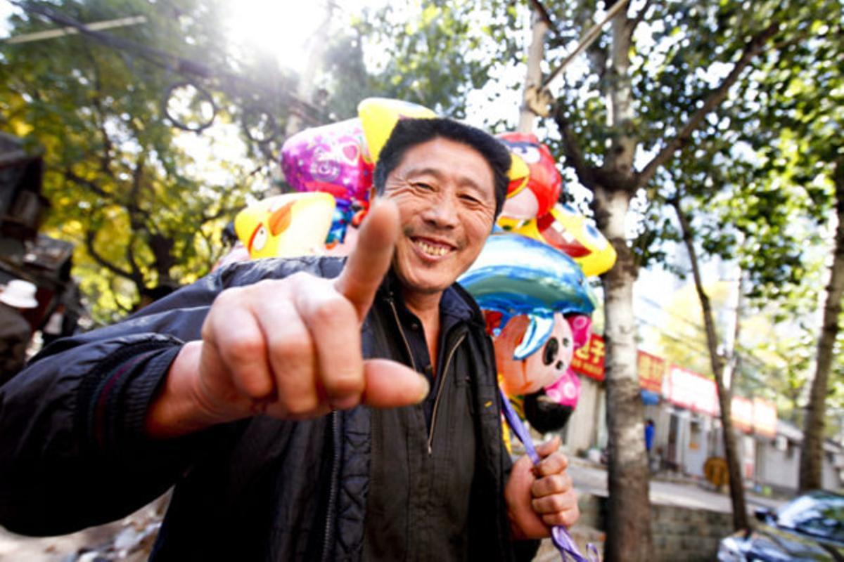 Un venedor de globus somriu en un carrer de Pequín (Xina).